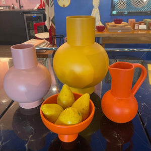 a grouping of 3 ceramic vases and a bowl filled with pears