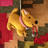 Small yellow dog ORNAMENT with a pink collar on a patterned fabric background