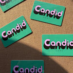 Green gift cards with 'Candid' text on a brown textured background